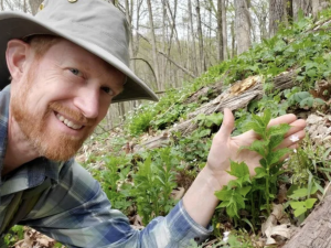 Image of DNR Biologist posing with plant unseen in Wisconsin since the 1950s.